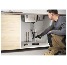 Handwerker verwendet den Stanley TradeLift zur Unterstützung einer Edelstahl-Spüle in einem Küchenschrank aus Holz während der Installation.
