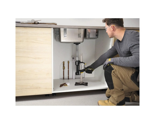 Handwerker verwendet den Stanley TradeLift zur Unterstützung einer Edelstahl-Spüle in einem Küchenschrank aus Holz während der Installation.