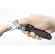 Hand hält ein Rautner Trapezmesser mit ergonomischem Griff während eines Klingenwechsels.