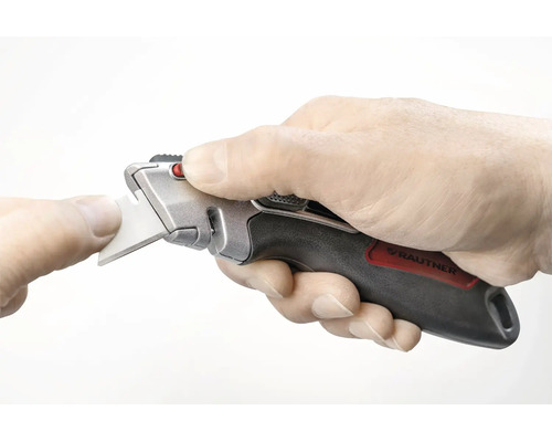 Hand hält ein Rautner Trapezmesser mit ergonomischem Griff während eines Klingenwechsels.