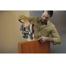 Mann verwendet einen Worx Akku-Nagler mit LED-Licht an einer Holzleiste.