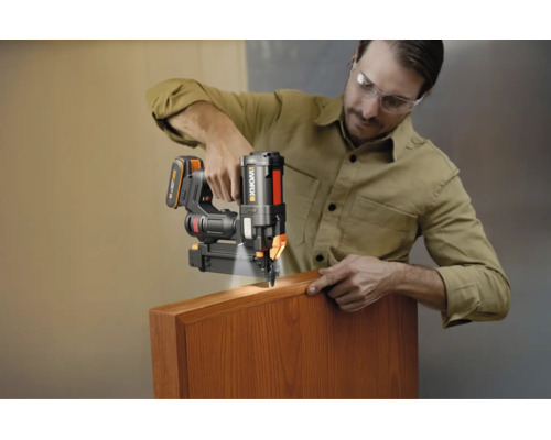 Mann verwendet einen Worx Akku-Nagler mit LED-Licht an einer Holzleiste.
