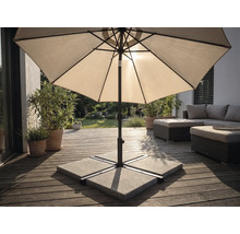 Sonnenschirm auf einer Holzterrasse mit Schirmständer aus Betonplatten, Gartenmöbeln und Pflanzen in einem hellen Außenbereich.