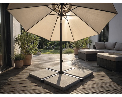 Sonnenschirm auf einer Holzterrasse mit Schirmständer aus Betonplatten, Gartenmöbeln und Pflanzen in einem hellen Außenbereich.