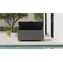 Moderne dunkelgraue Garten-Auflagenbox aus Metall mit Rollen und offenem Deckel, auf einer Terrasse neben einem Pool und Pflanzen.
