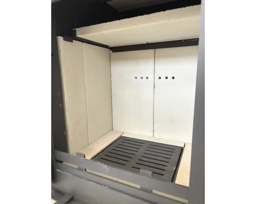 Brennraum eines Kaminofens mit Schamotteauskleidung und gusseisernem Rost