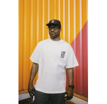 Mann trägt ein weißes Oversized T-Shirt aus Baumwolle mit Logo auf der Brust und eine schwarze Kappe.