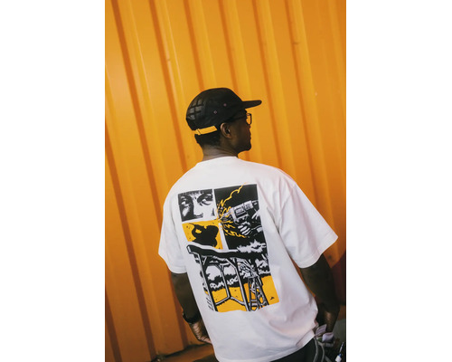 Mann in einem weißen T-Shirt mit schwarzem und gelbem Grafikdruck auf dem Rücken, der eine Bohrmaschine und Bauszenen zeigt.