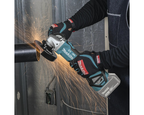 Eine Person nutzt einen Makita Akku-Winkelschleifer mit 18 Volt Akku an einem Metallrohr, während Funken fliegen.