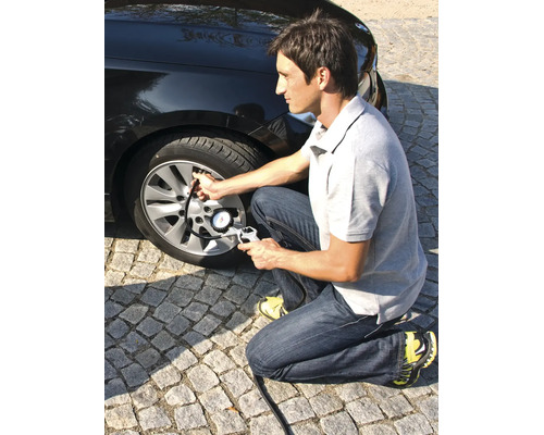 Mann prüft den Reifendruck an einem Auto mit einem Reifenfüller mit Manometer.