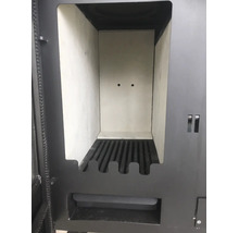 Geöffneter Brennraum eines Kaminofens mit Schamotteauskleidung und gusseisernem Rost.