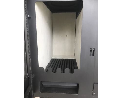 Geöffneter Brennraum eines Kaminofens mit Schamotteauskleidung und gusseisernem Rost.