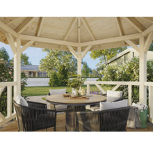 Moderner Gartenpavillon aus hellem Holz mit rundem Esstisch und dunklen geflochtenen Stühlen in einem hellen, gepflegten Garten.