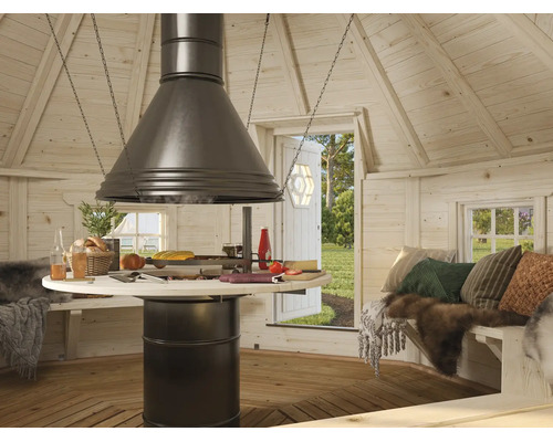Innenansicht einer hölzernen Grillhütte mit zentraler Feuerstelle, Dunstabzugshaube, rundem Tisch und Sitzbänken mit Kissen und Fellen.
