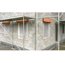 Rohbau aus Betonsteinen mit Gerüst, Fensteröffnungen mit Schutzfolie und Rollladenkästen auf einer Baustelle.