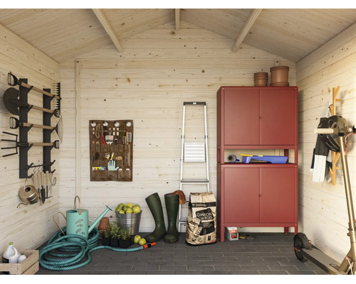 Hell eingerichtetes Inneres eines Holz-Gartenhauses mit rotem Metallschrank, Gartengeräten an der Wand, Schlauch und Stehleiter.