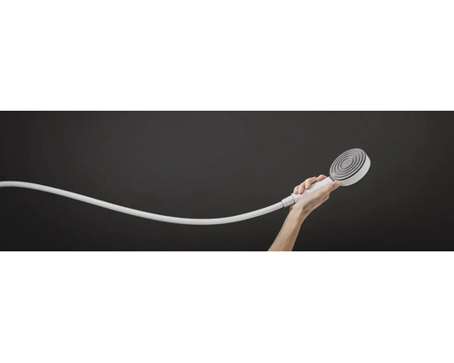 Eine Hand hält eine runde Handbrause mit Duschschlauch vor einem neutralen Hintergrund