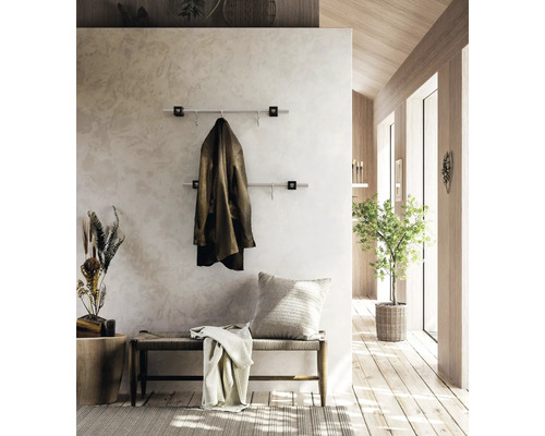 Moderne Wandgarderobe mit zwei Edelstahlstangen im hellen Vorzimmer mit Holzelementen, einer Sitzbank und Zimmerpflanze.