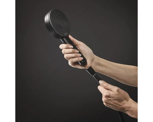 Eine Hand schraubt eine runde Hansgrohe Handbrause an einen Brauseschlauch.