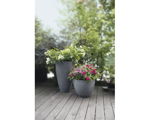 Zwei graue, strukturierte Kunststoff-Pflanzkübel mit Blumen auf einer Holzterrasse im Garten.