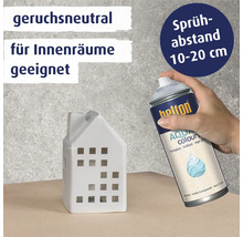Hand sprüht Belton Aqua Colours Klarlack auf ein weißes Hausobjekt mit Informationen zu Geruchsneutralität und Sprühabstand.