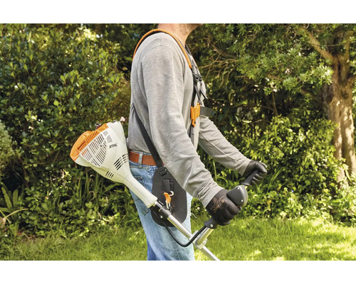 Eine Person trägt einen Stihl Freischneider mit einem bequemen Tragegurt im Garten für ergonomische Mäharbeiten.