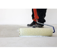 Person beim Auftragen von Grundierung oder Farbe auf einen Boden mit einer Farbwalze