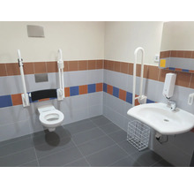 Barrierefreies Badezimmer mit wandhängendem WC, Stützklappgriffen, Waschbecken, Seifenspender und Kacheln in verschiedenen Farben.
