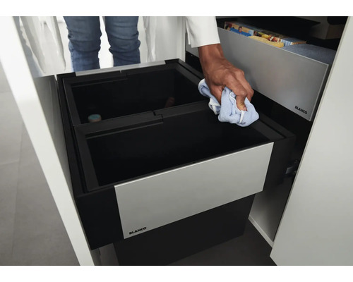 Einbauabfalltrennsystem von Blanco in einem Küchenschrank mit Person, die den Behälter mit einem Tuch reinigt.