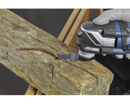 Ein Oszillationswerkzeug mit StarlockPlus Aufnahme sägt einen rostigen Nagel in einem Holzbalken durch.