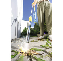Person verwendet einen Gas Unkrautbrenner zur thermischen Unkrautbekämpfung auf einer gepflasterten Fläche im Außenbereich.