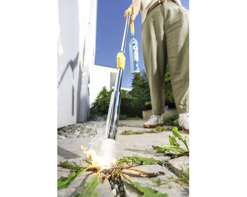 Person verwendet einen Gas Unkrautbrenner zur thermischen Unkrautbekämpfung auf einer gepflasterten Fläche im Außenbereich.