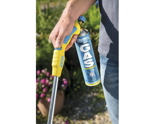 Eine Person hält einen Gloria Thermoflamm Gasbrenner mit Gaskartusche im Garten zur Unkrautbekämpfung.