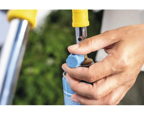 Hand bedient das Regulierventil einer Gasflasche fuer einen Abflammgeraetaufsatz