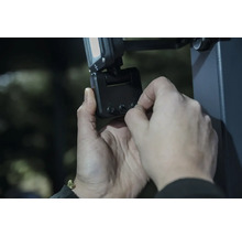 Eine Person stellt einen LED Strahler mit Bewegungsmelder manuell an den Drehreglern ein.