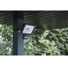 LED Strahler mit Bewegungsmelder an einem Pfosten montiert zur Außenbeleuchtung im Garten