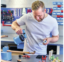 Ein Handwerker lötet ein Kupferrohr mit einem Lötbrenner in einer Werkstatt.