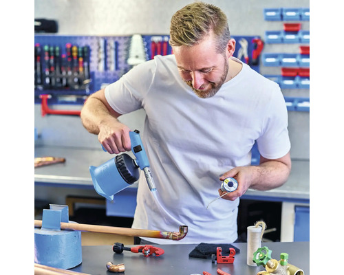 Ein Handwerker lötet ein Kupferrohr mit einem Lötbrenner in einer Werkstatt.