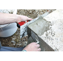 Handwerker glättet mit einer Glättkelle und einer Abziehlatte eine Betonmauer für ein ebenes Ergebnis.