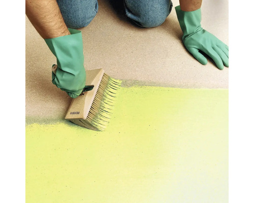 Person mit Handschuhen streicht eine Fläche mit einem großen Flächenstreicher aus Holz.