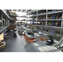 Weitlaeufiges Autohaus mit mehreren Ebenen, Glasfassade und zahlreichen ausgestellten Fahrzeugen in einer modernen Architektur.