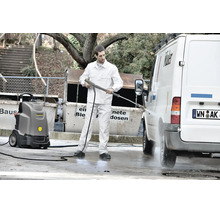 Ein Mann reinigt mit einem Karcher Hochdruckreiniger ein weißes Fahrzeug auf einem Betriebshof.