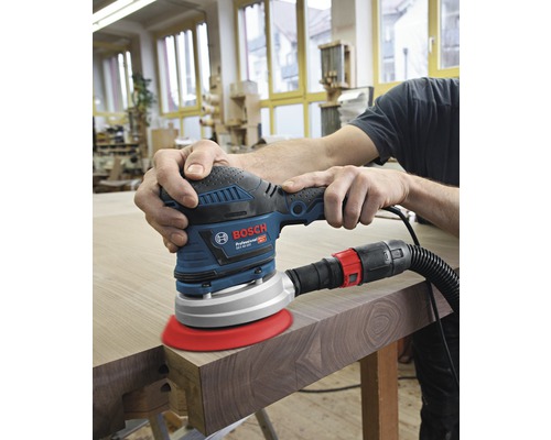 Eine Person schleift Holz mit einem Exzenterschleifer von Bosch.