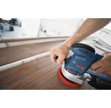 Ein Mann schleift ein Holzdeck mit einem Exzenterschleifer von Bosch