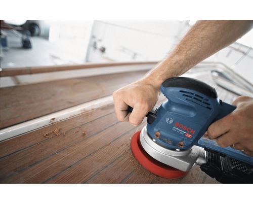Ein Mann schleift ein Holzdeck mit einem Exzenterschleifer von Bosch