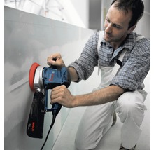 Mann schleift Wand mit einem Trockenbauschleifer von Bosch