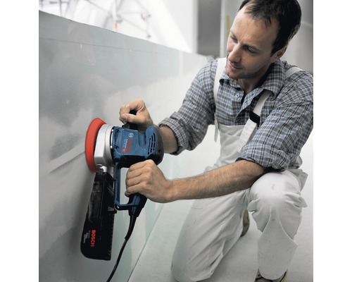 Mann schleift Wand mit einem Trockenbauschleifer von Bosch