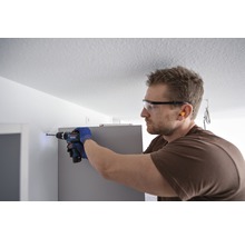 Handwerker bohrt mit Bohrmaschine ein Loch in die Wand.