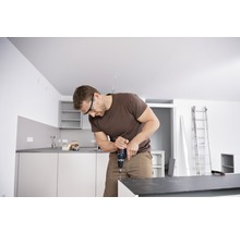 Mann montiert Küche mit Akkubohrer und Schutzbrille