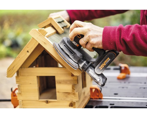 Eine Person schleift ein Vogelhaus mit einem Exzenterschleifer von Worx.